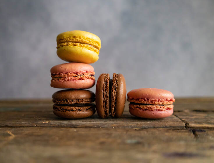 A stack of macarons sit on a slab of old wood