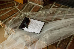 A wedding invitation and veil lay on a brick fireplace