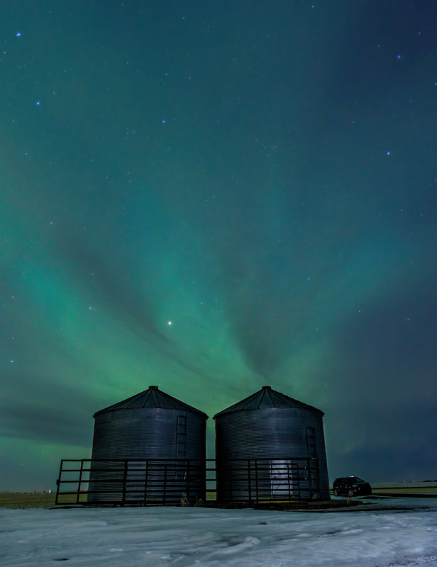 Bands of green Aurora over 2 silos