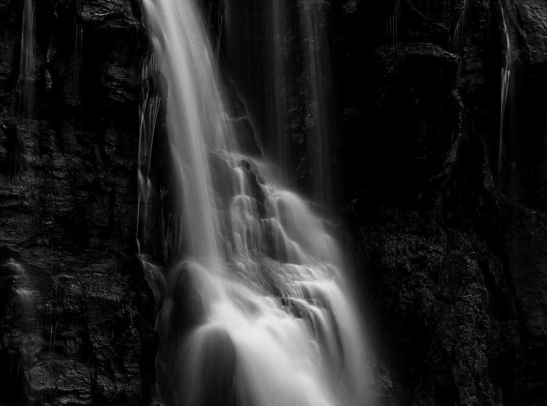 A black and white image of water plunging down a rock face