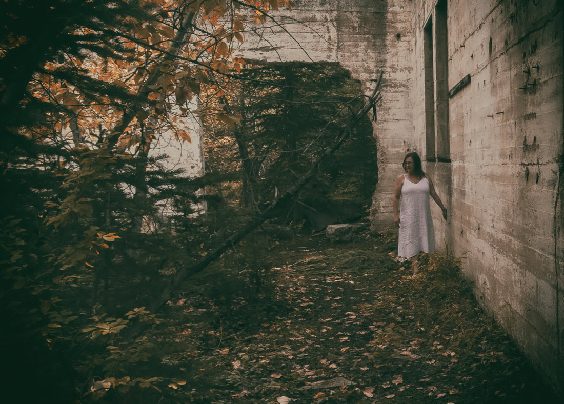 a girl walks through an overgrown abandoned building