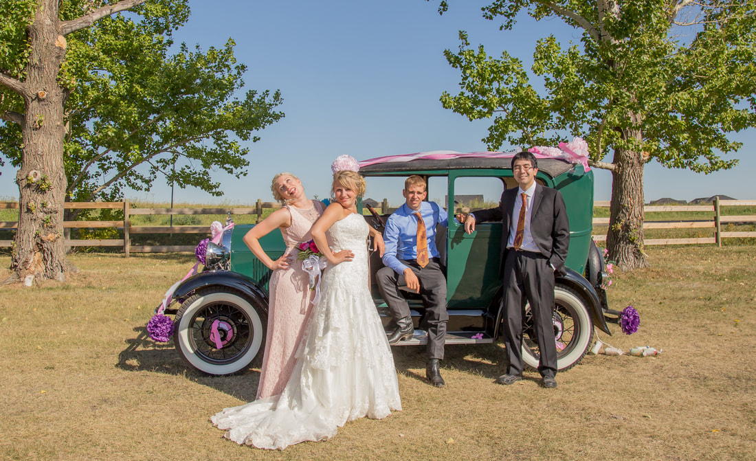 the bridal party pose in front a vintage car