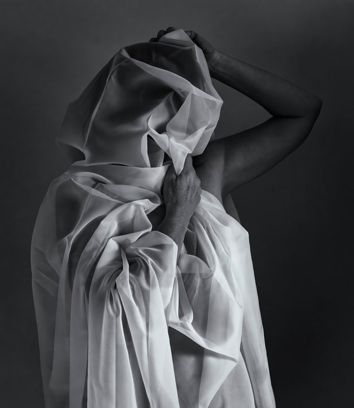 low key black and white image of a girl wrapped in a white shear material