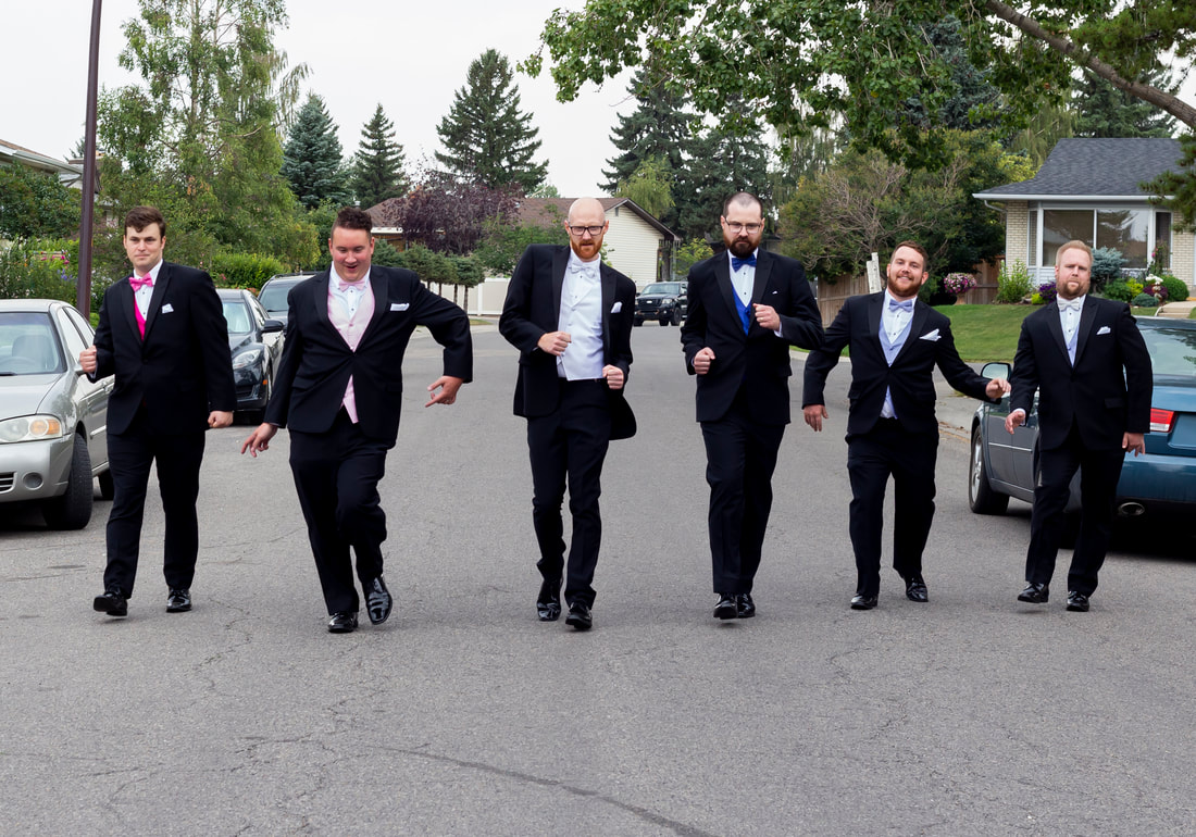 groom and party walk silly down the road