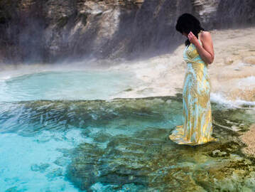 Kelly wears a shimmering blue and gold dress while standing in aquamarine coloured water